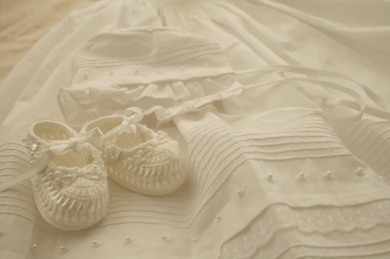Weiße Babykleidung und gehäkelte Schühchen