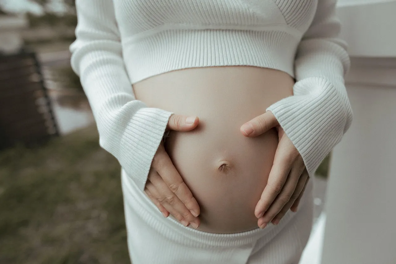 Schwangere Frau legt die Hände auf ihren Bauch
